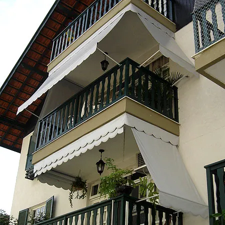 Toldo cortina em sacada com braços móveis e grades trabalhadas