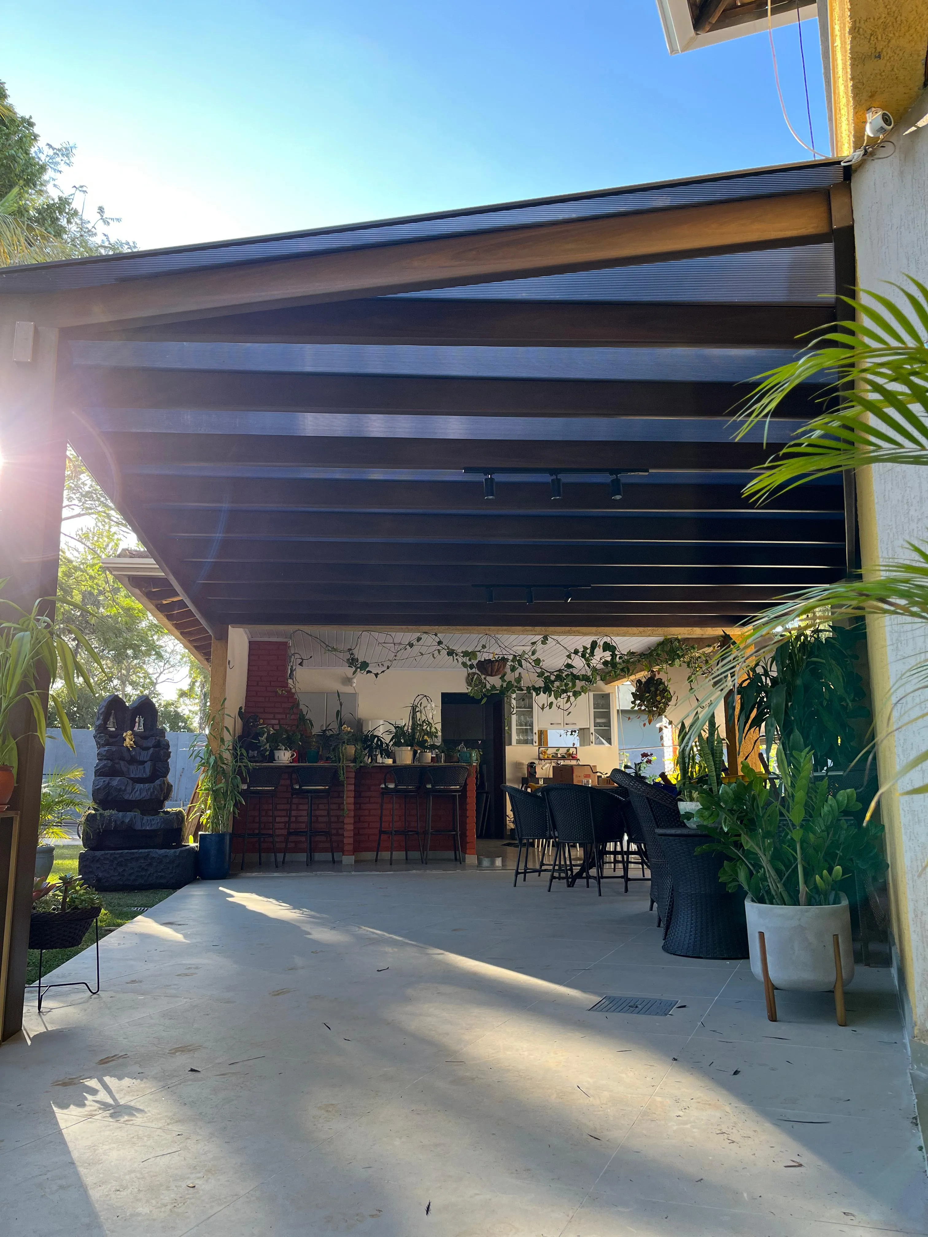 Pergolado sobre área gourmet com bar ao entardecer