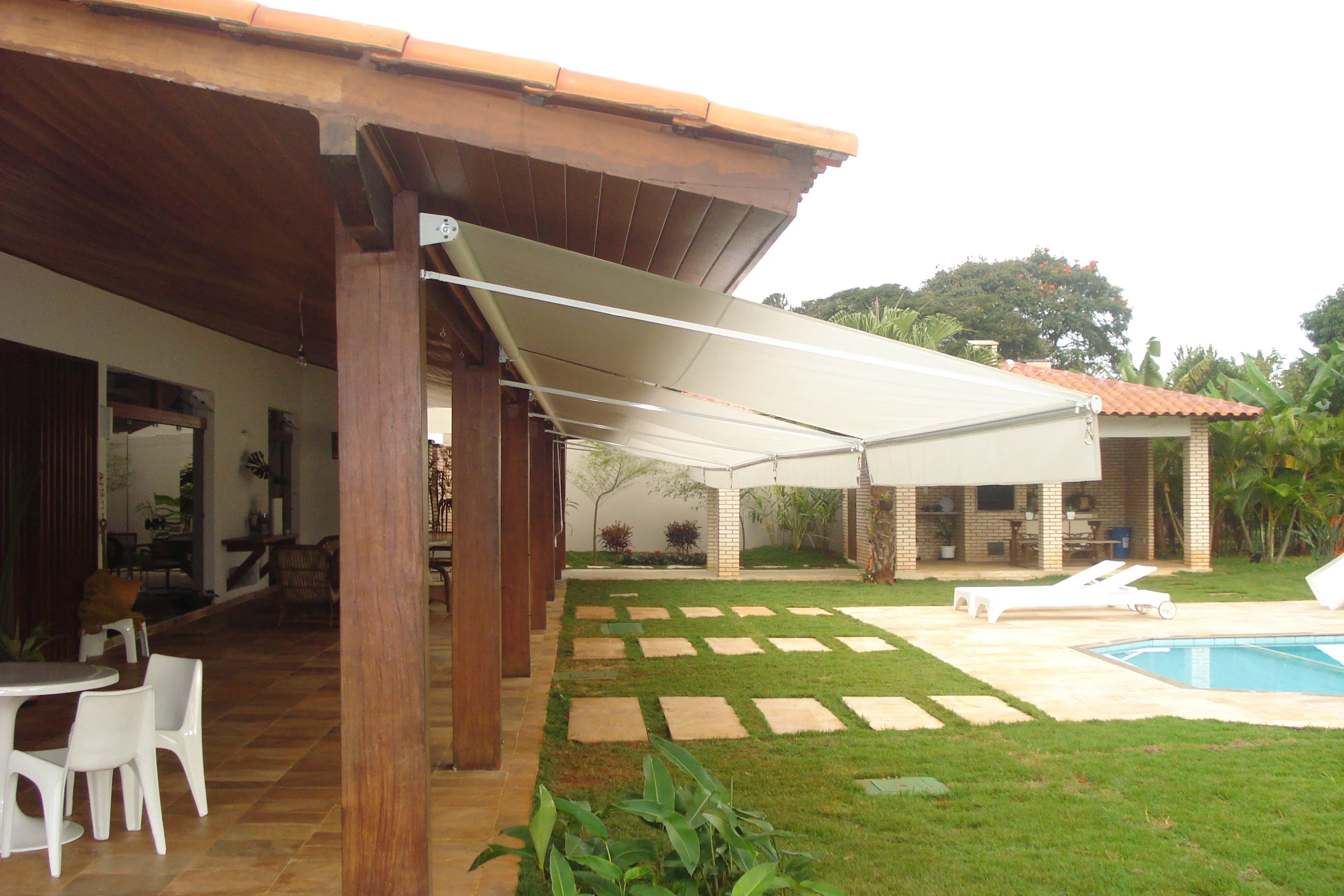 Toldo cortina de alumínio totalmente aberto sobre área de piscina