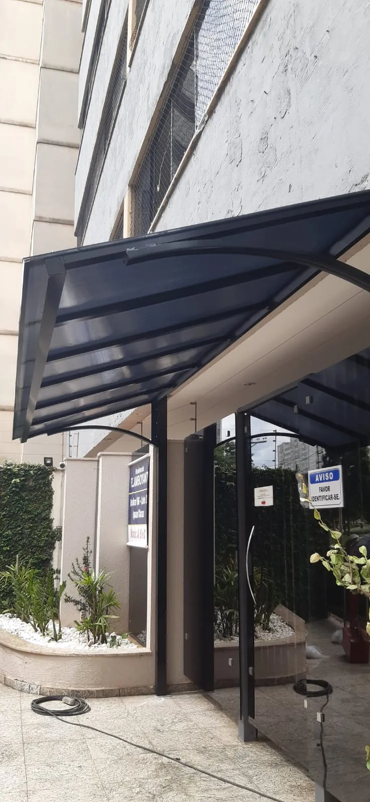 Cobertura de policarbonato azul-marinho em entrada de prédio