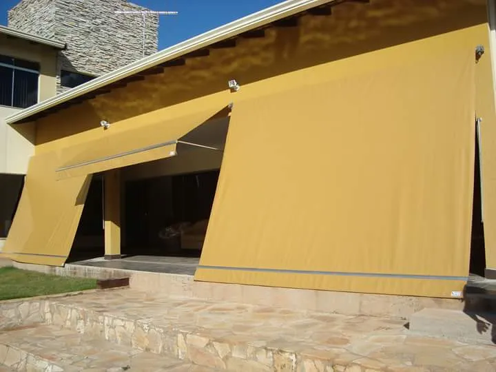Toldo cortina amarelo vibrante em casa de pedra