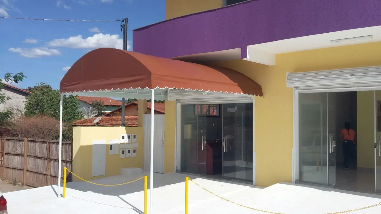 Cobertura fixa em lona terracota em formato de arco na entrada de um comércio