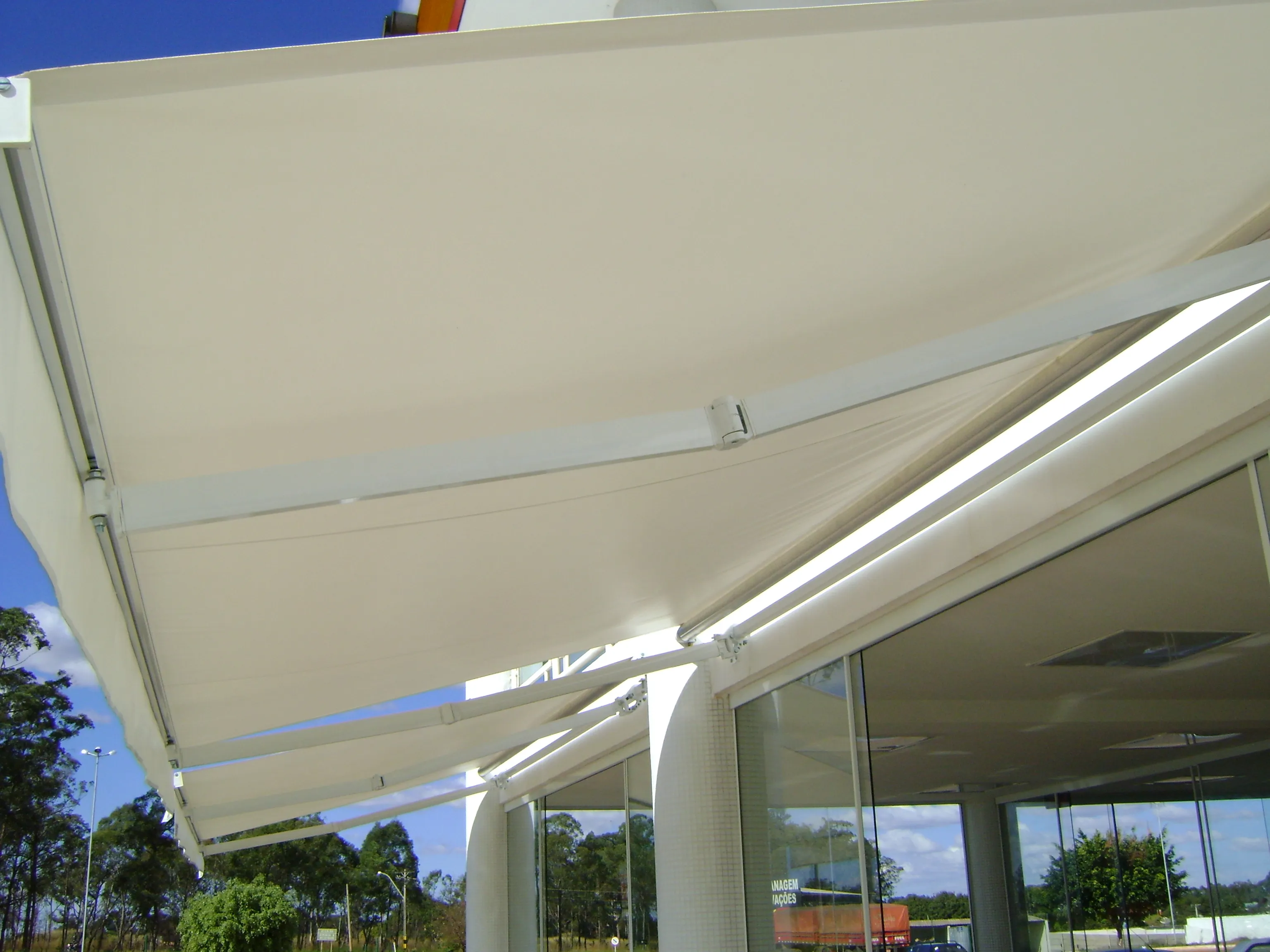 Toldo italiano articulado em fachada comercial de vidro