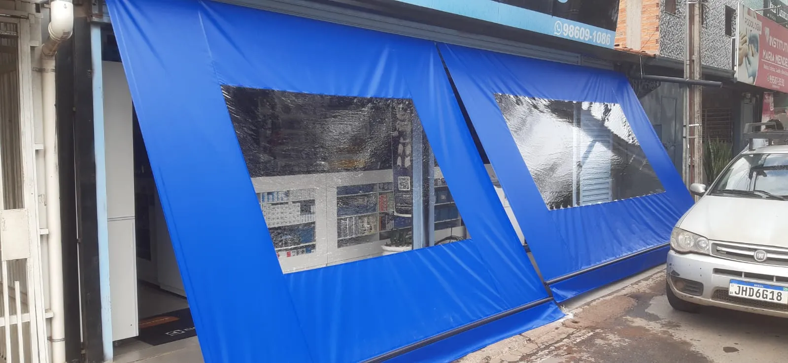 Toldo cortina azul com visor de vinil em fachada comercial