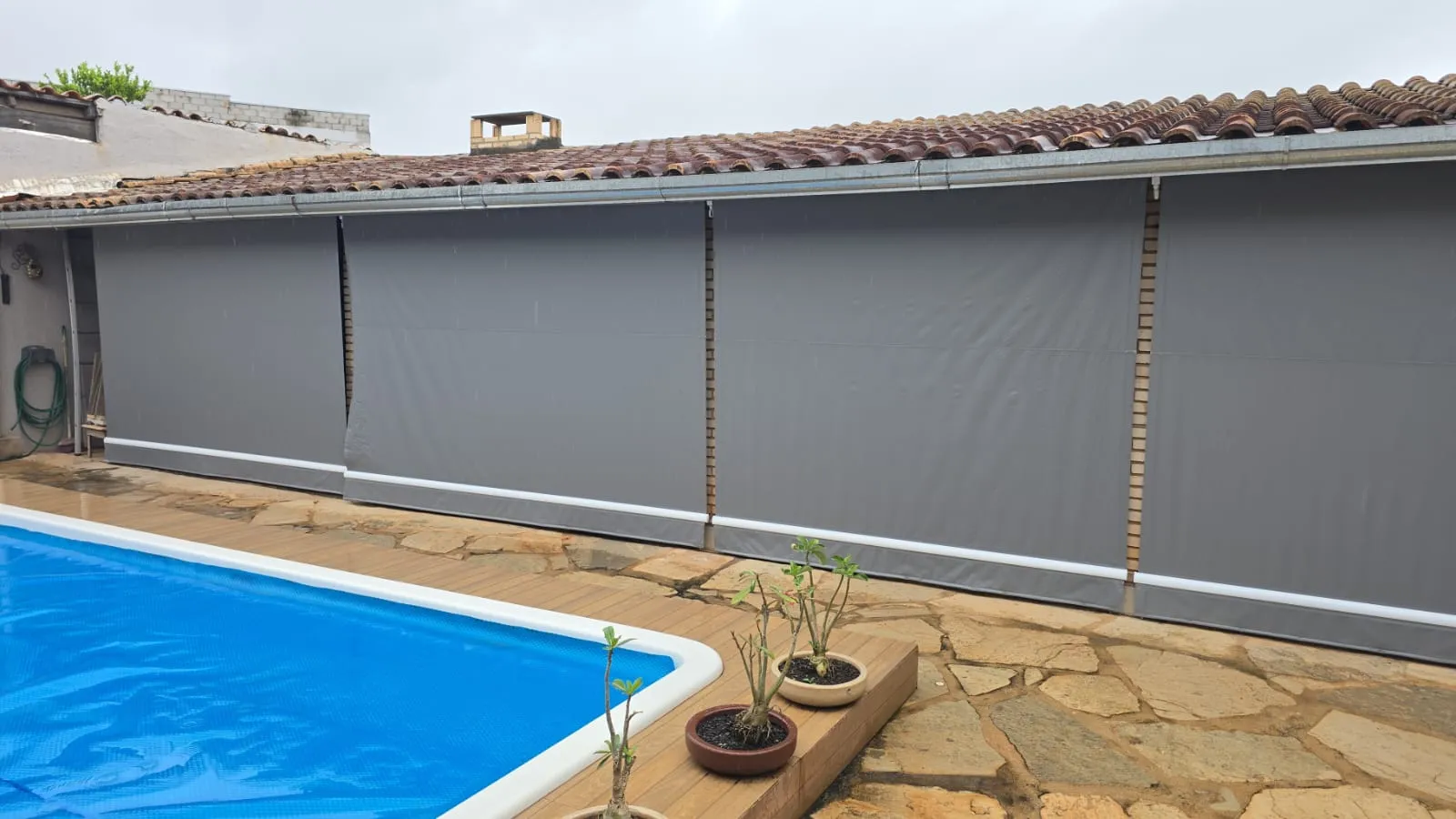 Toldo cortina cinza-claro fechado em área de piscina