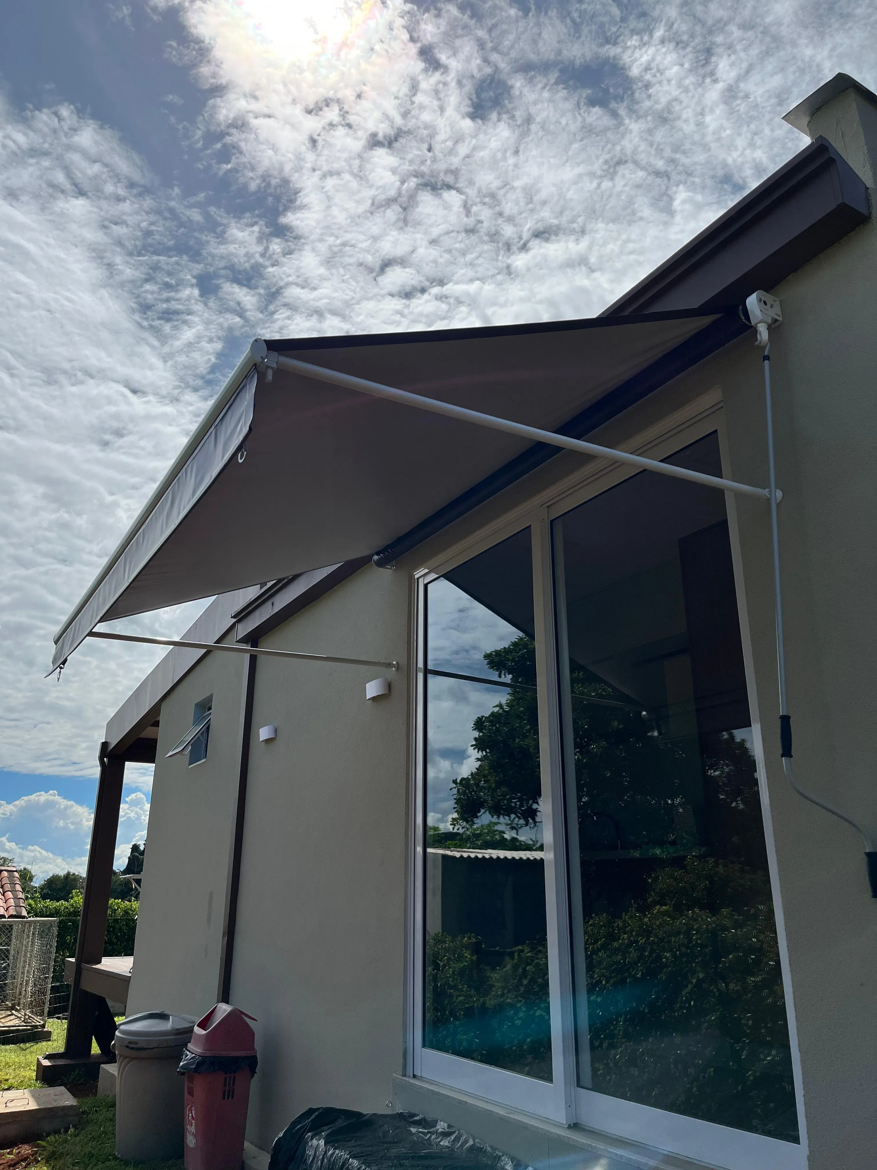 Toldo cortina aberto mostrando o mecanismo, com céu dramático ao fundo
