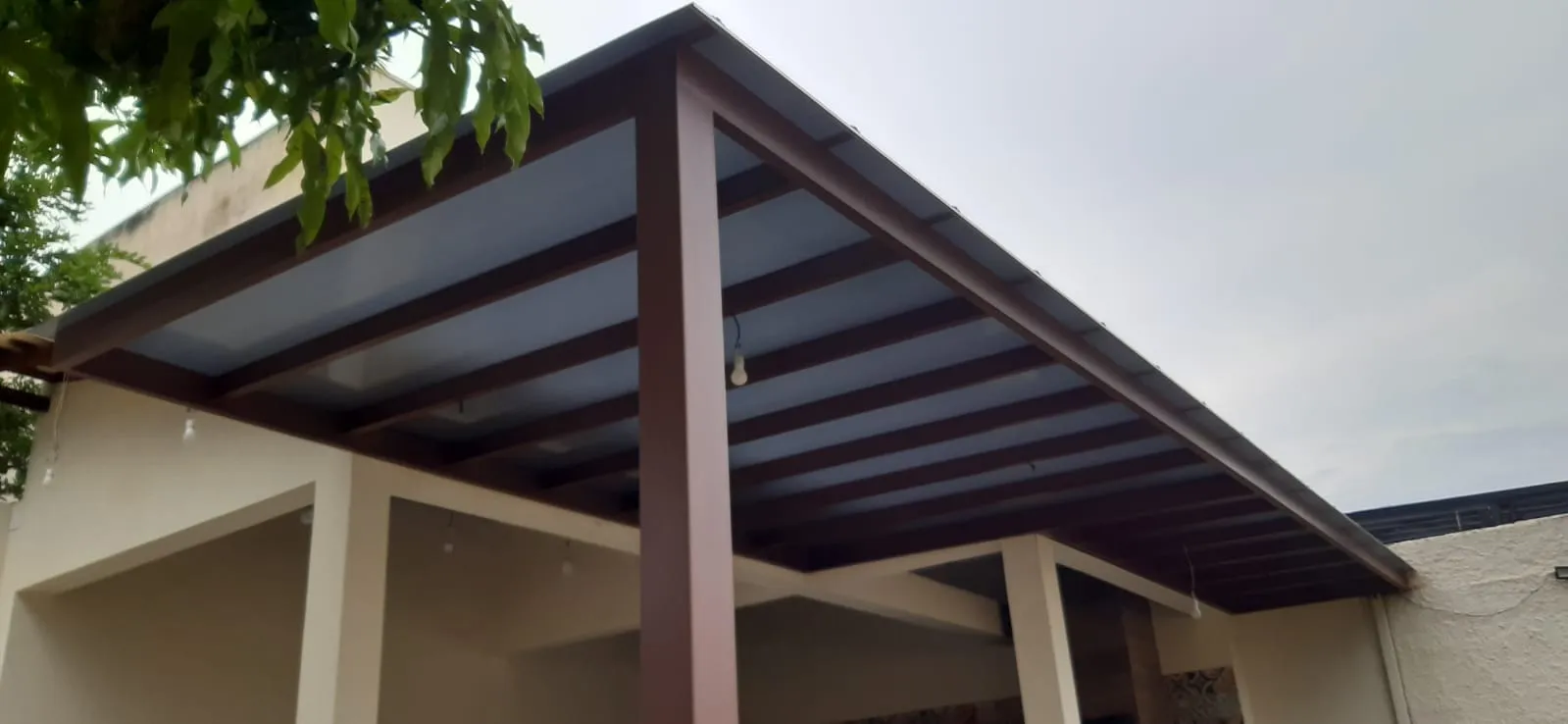 Pergolado em tom de madeira avermelhado com luminária pendente
