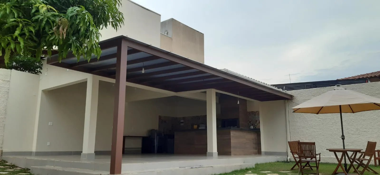 Pergolado com mobiliário completo, mesa e guarda-sol