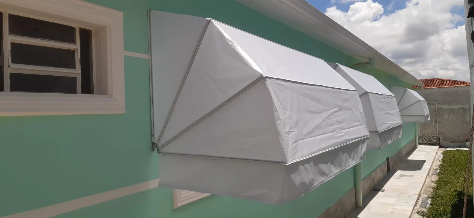 Toldos Mediterrâneo brancos em fachada com parede verde-menta