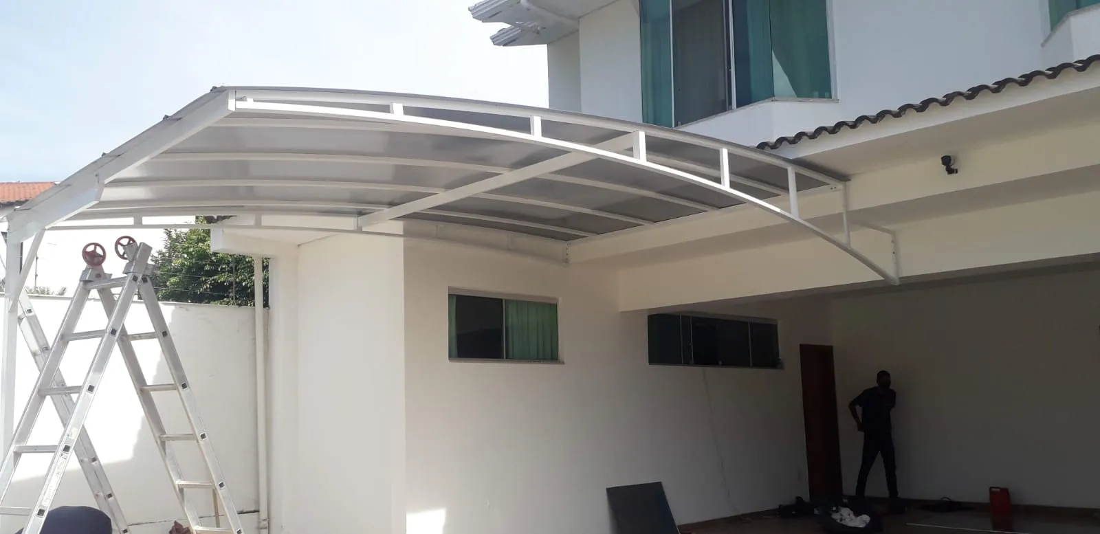 Cobertura de policarbonato cristal sobre garagem de casa moderna