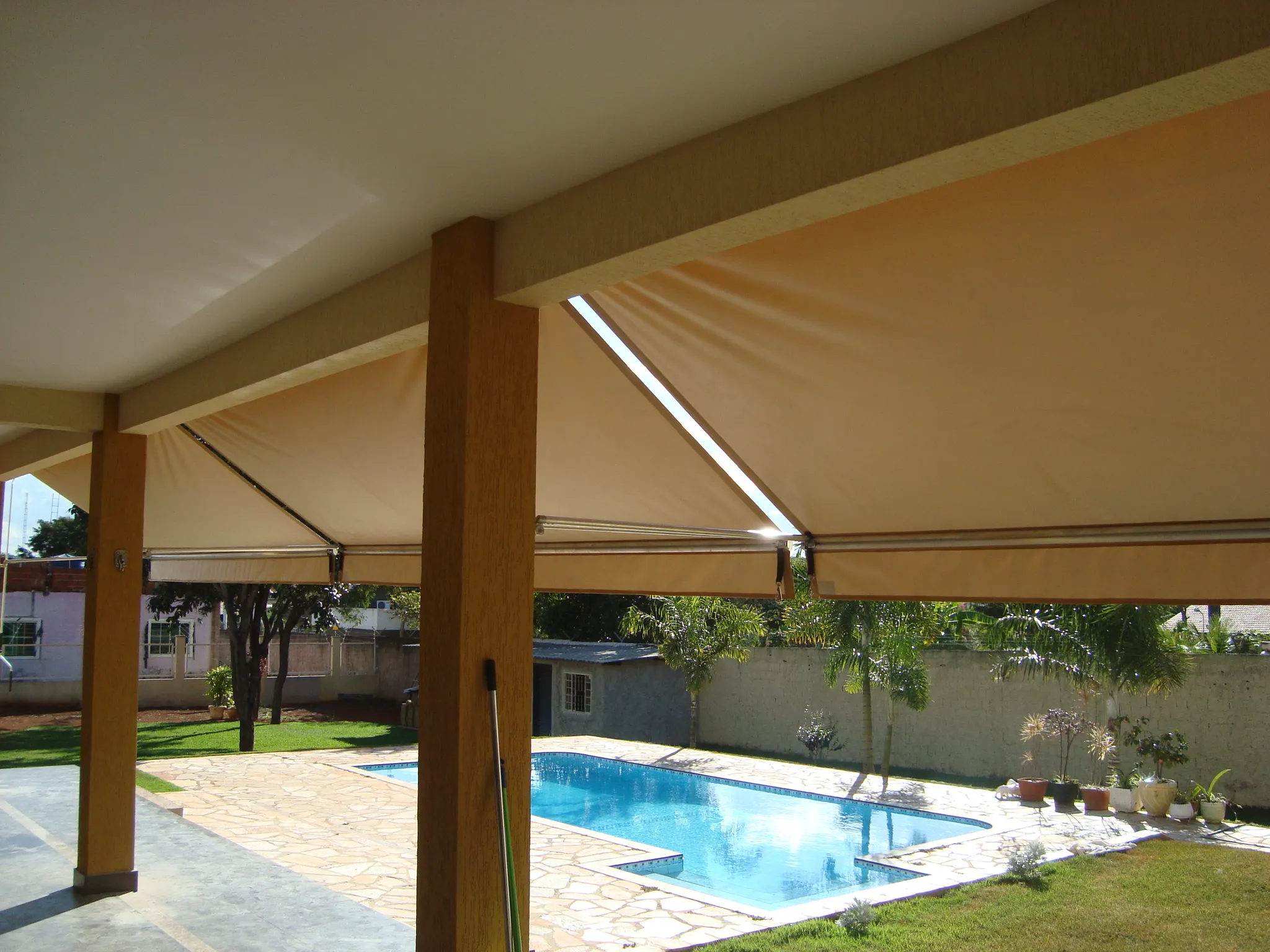 Várias unidades de toldo cortina abertas sobre piscina e área gourmet